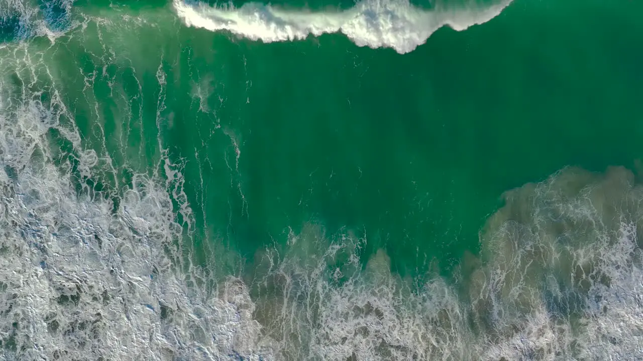 Aerial View Of Foamy Waves Rolling On Beach In Slow Motion