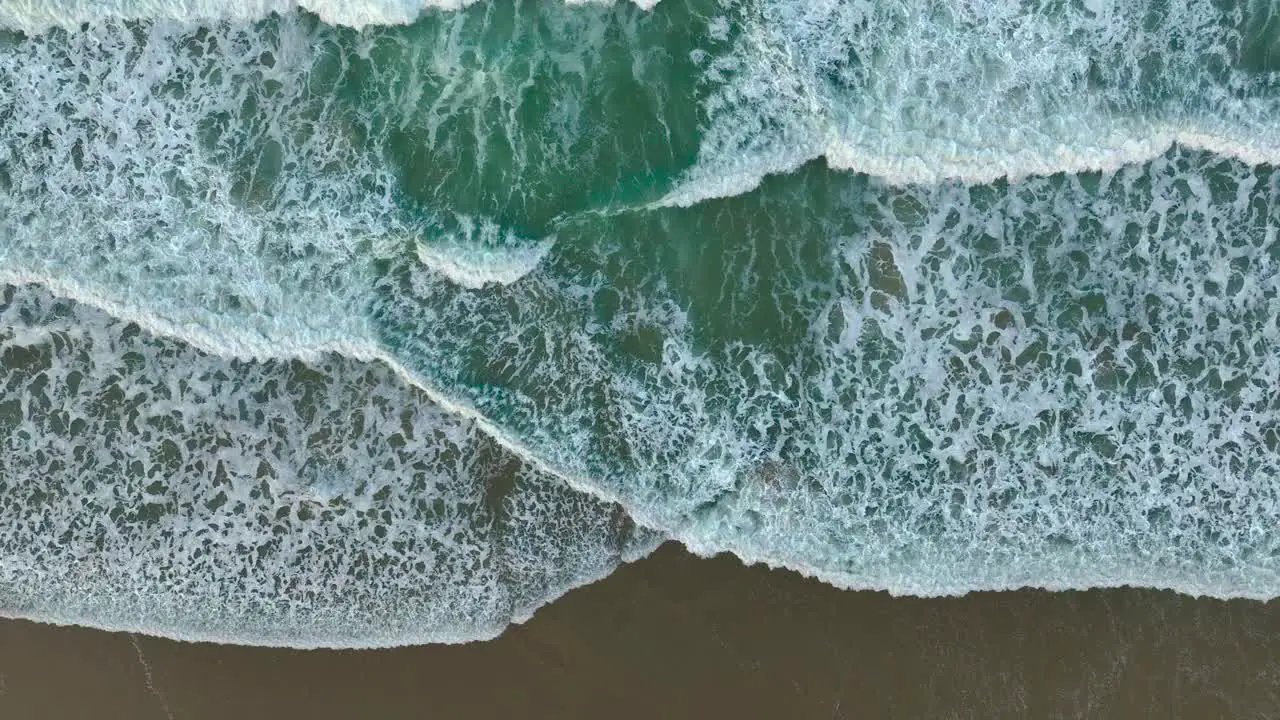 Foamy Waves Splashing Sandy Shore Of The Beach Aerial Top Down