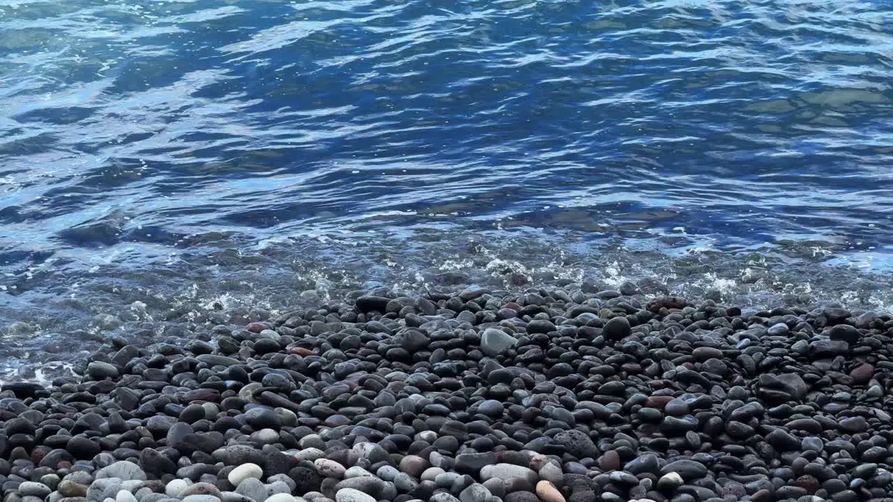 Beach waves washing on pebble stone beach Tenerife South Spain