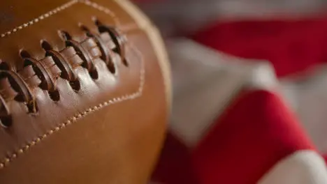 Close Up Shot Of Person Picking Up American Football With Stars And Stripes Flag In Background 1