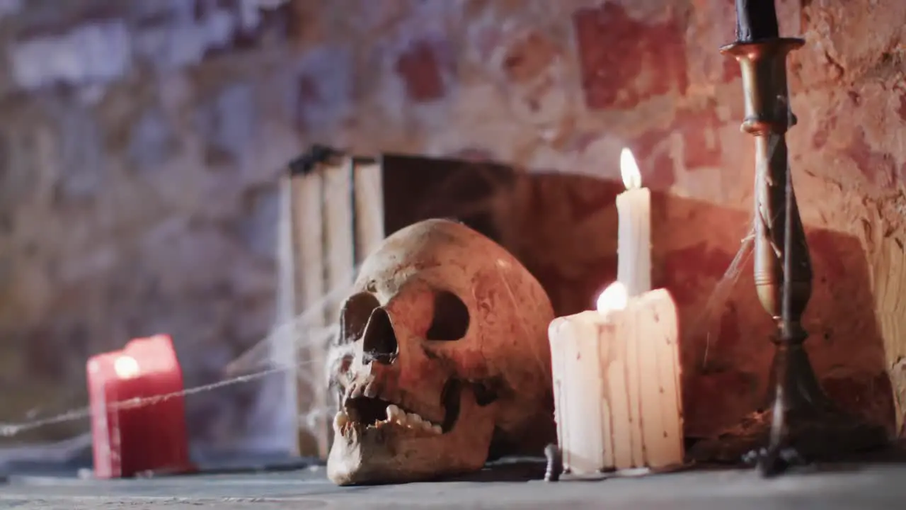 Video of stack of books with spider web skull and candles on brick wall background