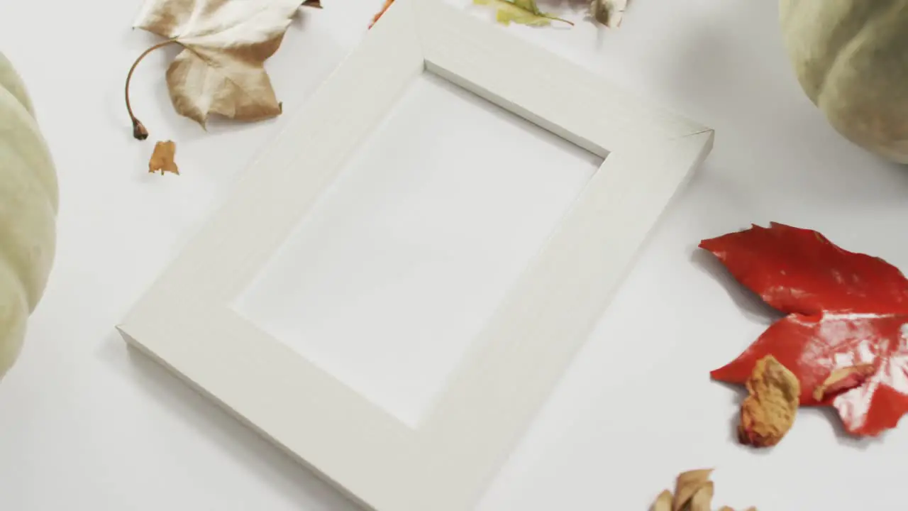 Empty frame with copy space pumpkin and autumn leaves against white background