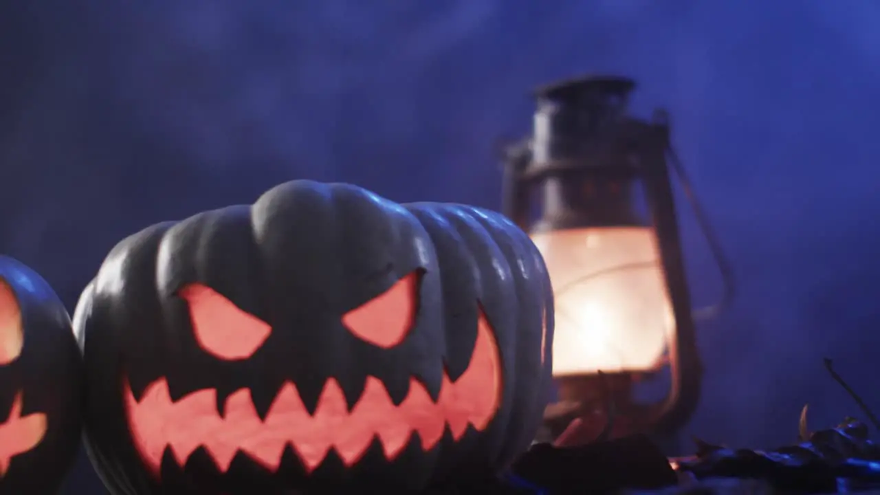 Video of halloween carved pumpkins lantern and smoke with copy space on purple background