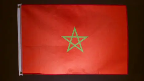 Studio Shot Of Flag Of Morocco Falling Down Against Black Background