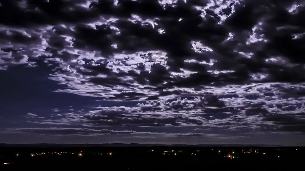 Dramatic night timelapse of cloud passing over head at night and reflecting the moon light over Moroccan city