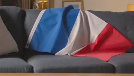 Flag Of France Draped Over Sofa At Home With Football Ready For Match On TV