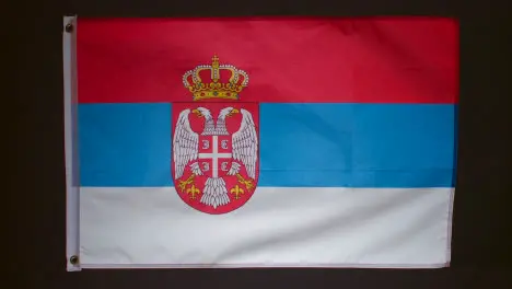 Studio Shot Of Flag Of Serbia Falling Down Against Black Background