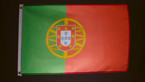 Studio Shot Of Flag Of Portugal Falling Down Against Black Background