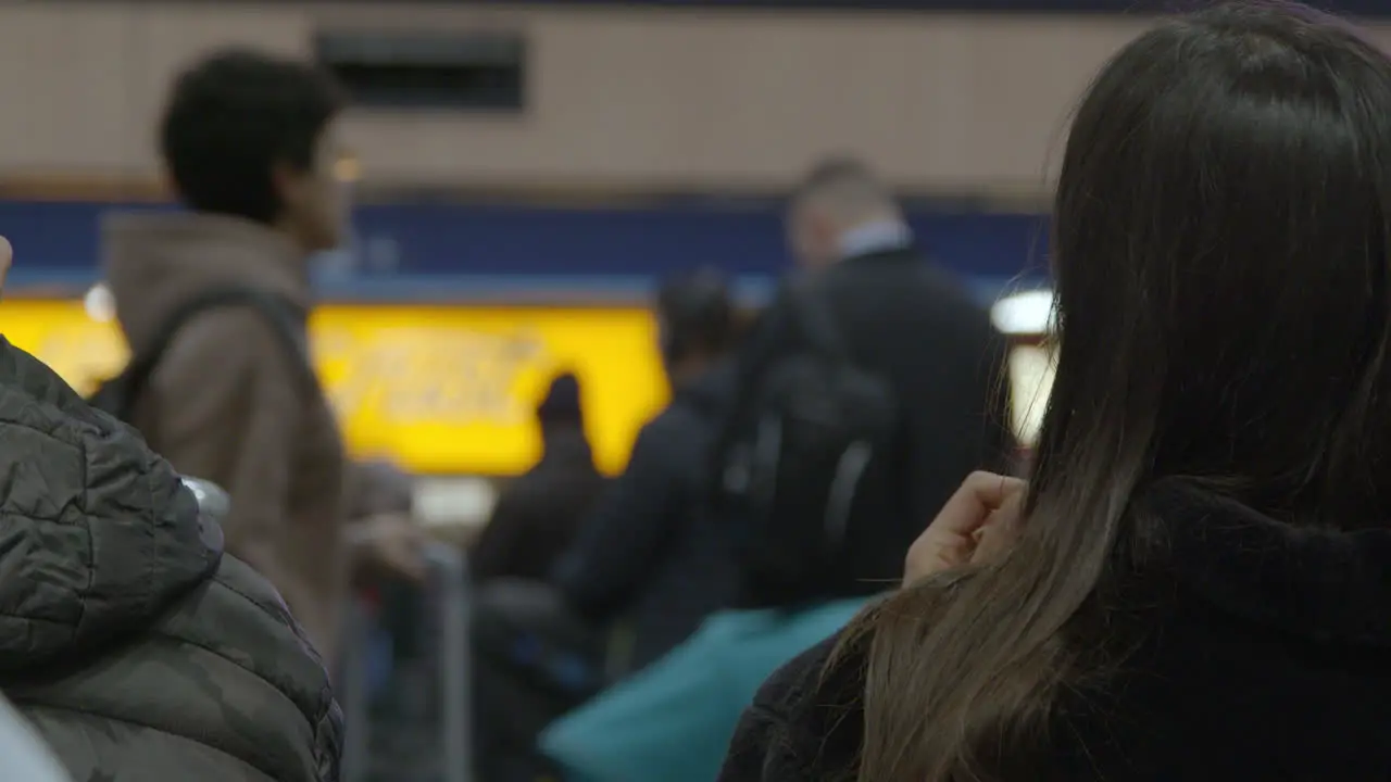 Woman puts on earphones in train station with people passing