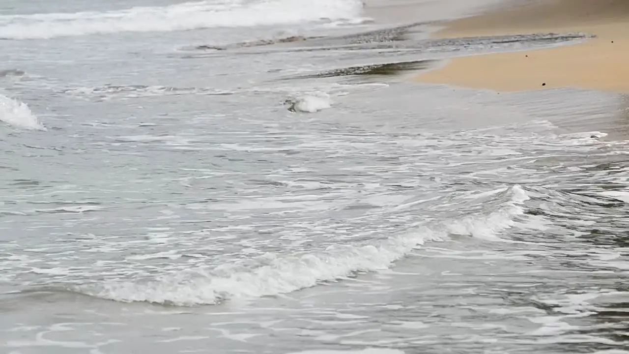 Close up shot of small waves crashing ashore at the Caribbean sea on a cloudy afternoon