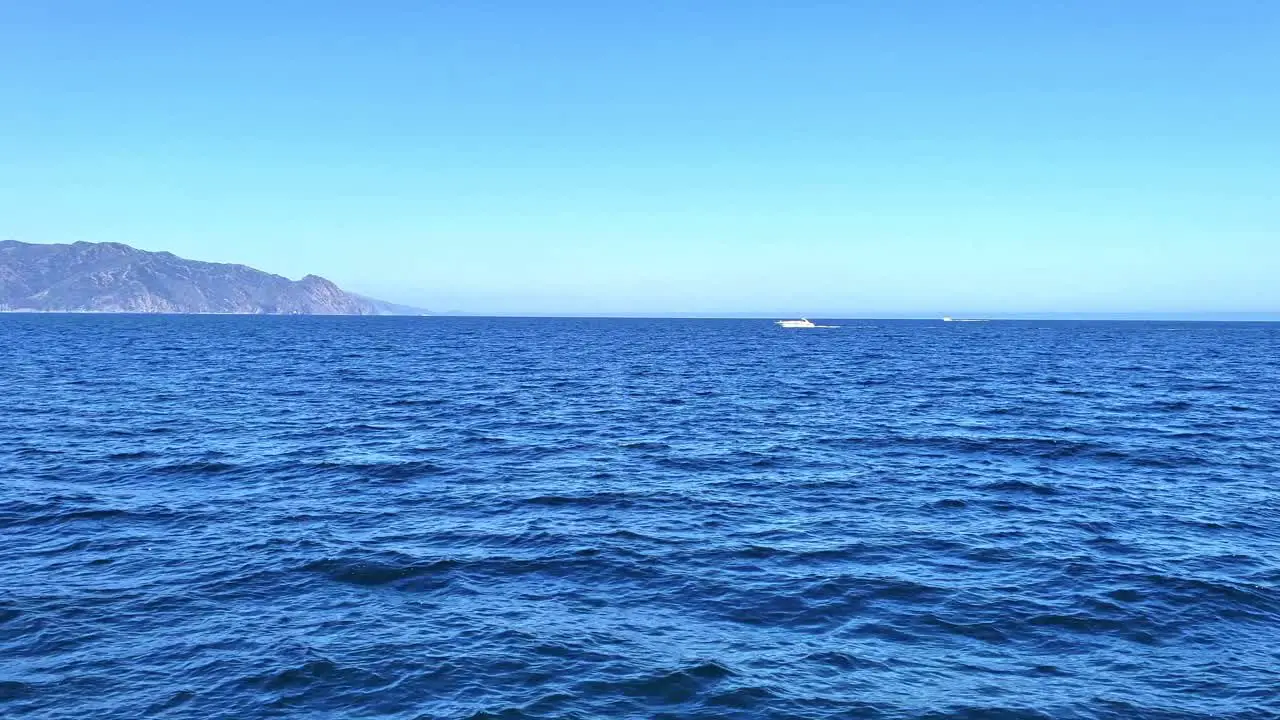 Island in the distance view from the ocean with boat of to the side blue water and sky