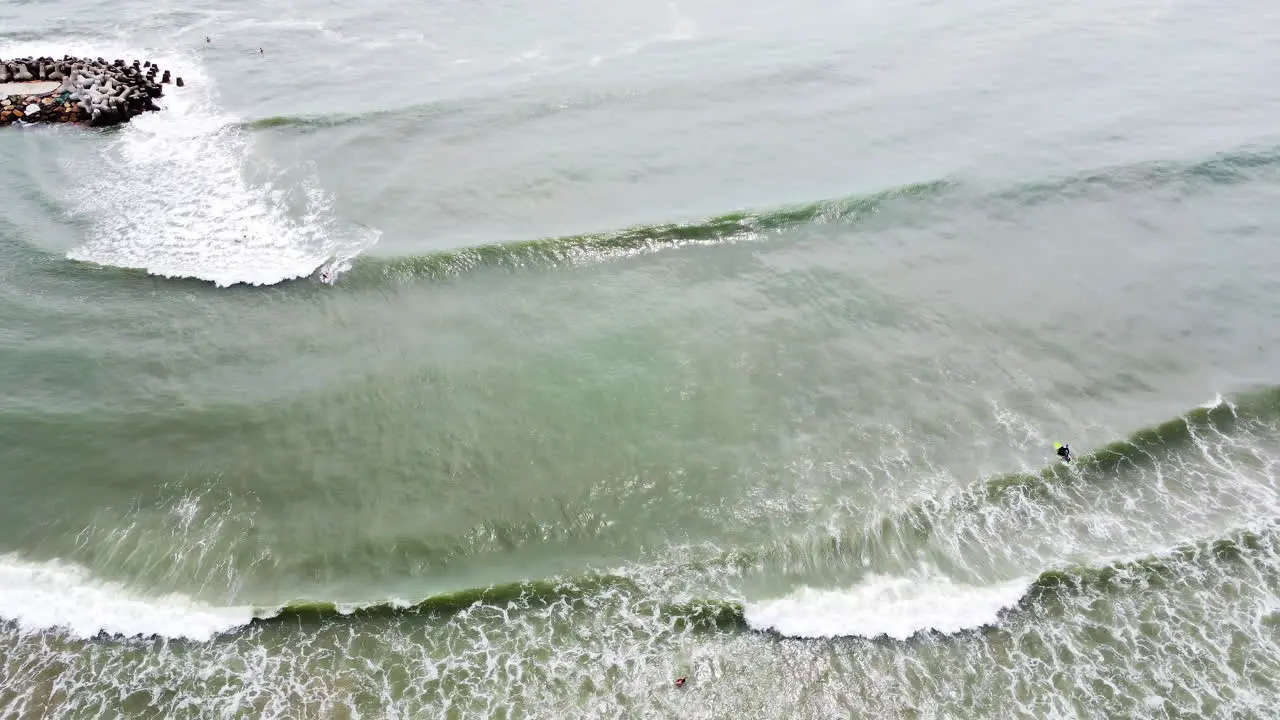 A vertical shot of the waves hitting the shore of Sea Links Beach while a few surfers are hanging out on the water