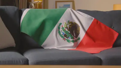 Flag Of Mexico Draped Over Sofa At Home Ready For Match On TV