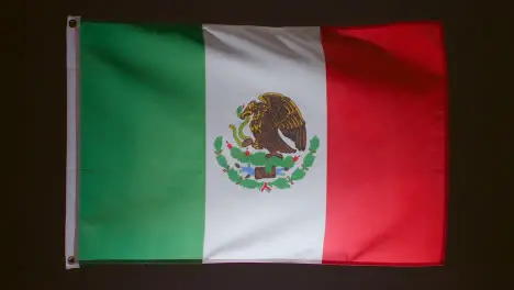 Studio Shot Of Flag Of Mexico Falling Down Against Black Background