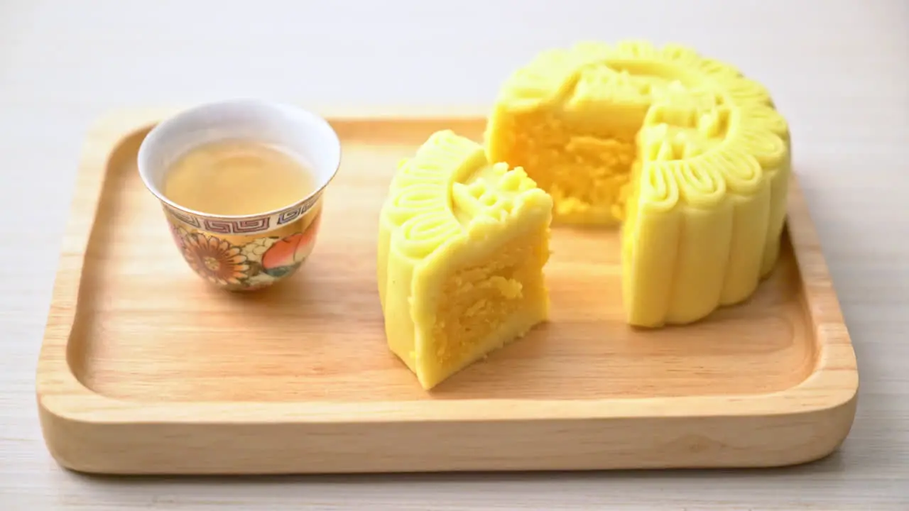 Chinese moon cake custard flavour with tea on wood plate