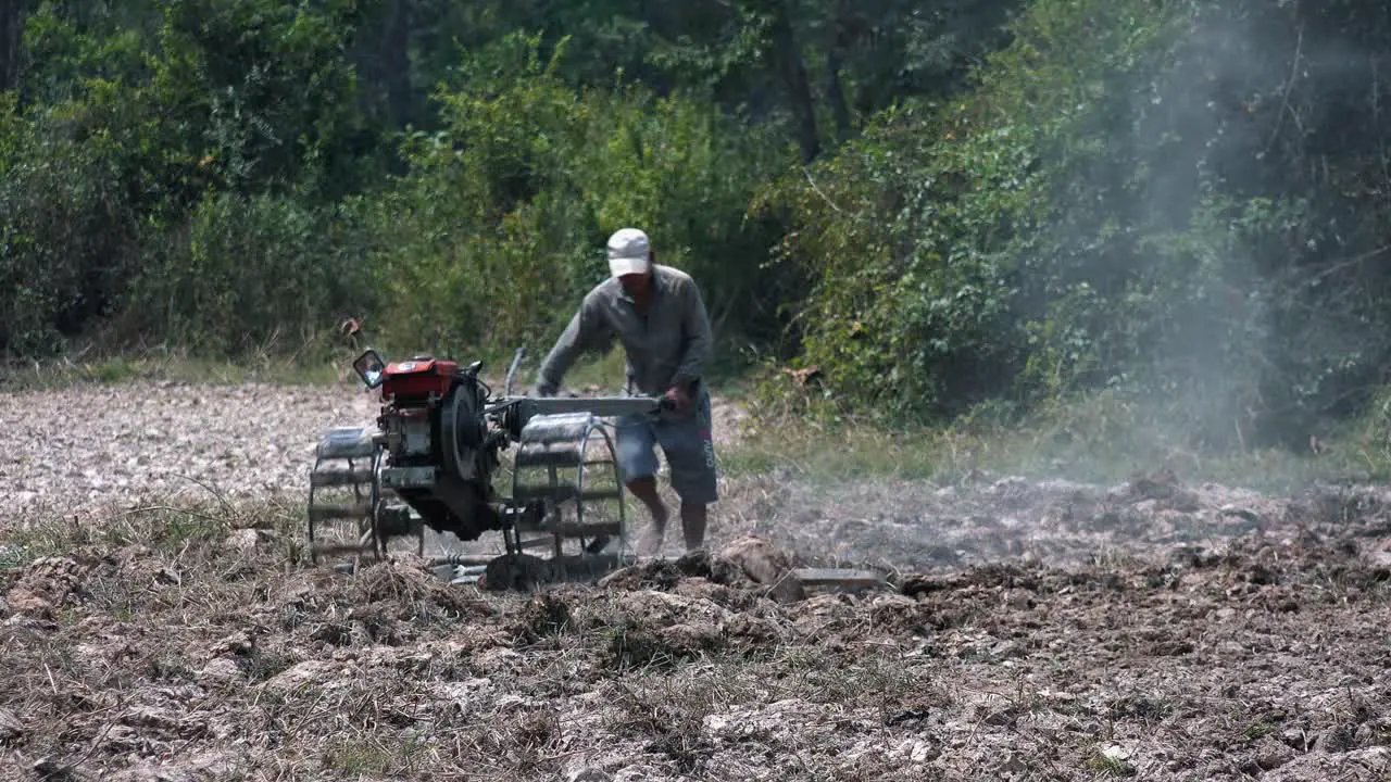 Wide Exterior Static Shot of a Farmer on Ploughing Machine the Field in the Day