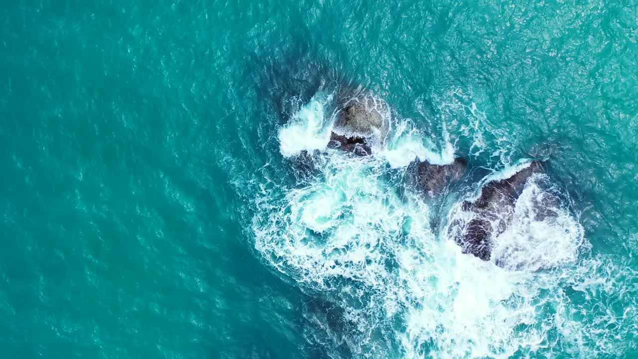 Foamy waves crashing on the boulders in the aquamarine sea