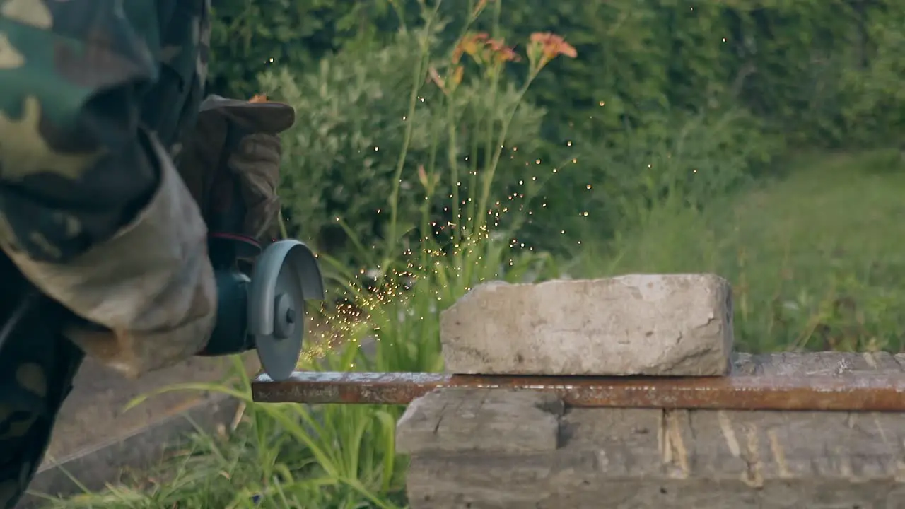 slow motion man in camouflage cuts metal with circular saw