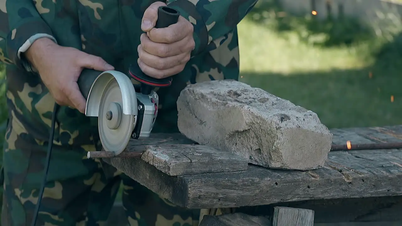 craftsman cuts metal rod with modern instrument in yard