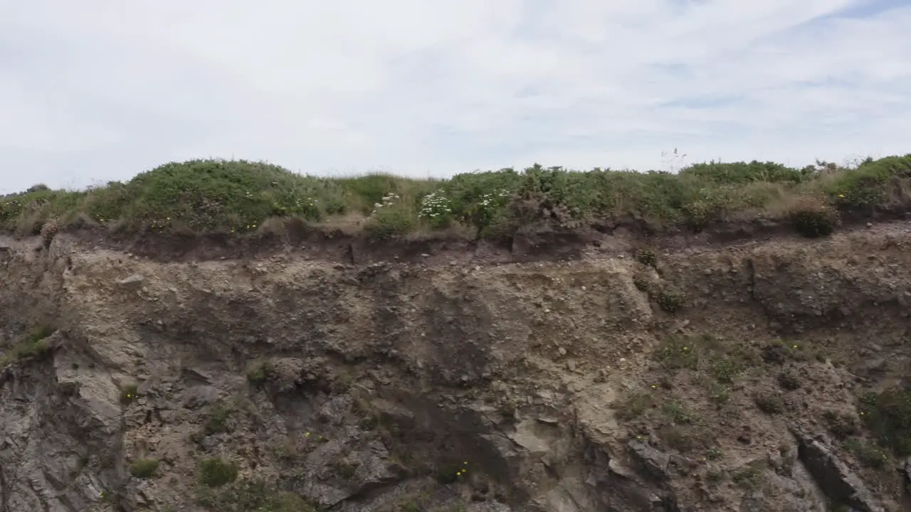 Packed sedimentary conglomerate caps rocky cliffs green grass on top