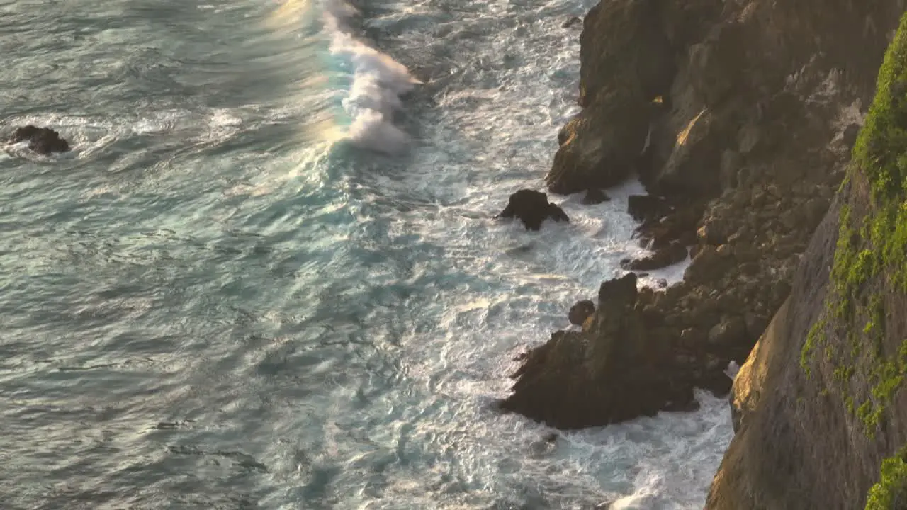 Large waves crashing on rocky tropical island shore turbulent surface white foam