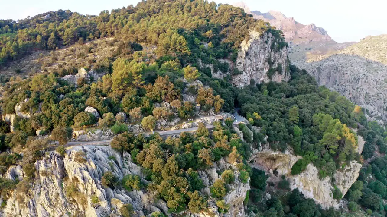 Steep road on the edge of a mountain range on sunny day rotate drone shot