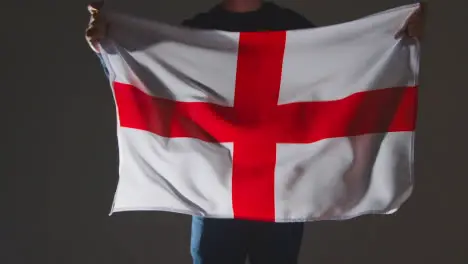 Studio Shot Of Anonymous Person Or Sports Fan Waving English Flag Of Saint George Against Black Background