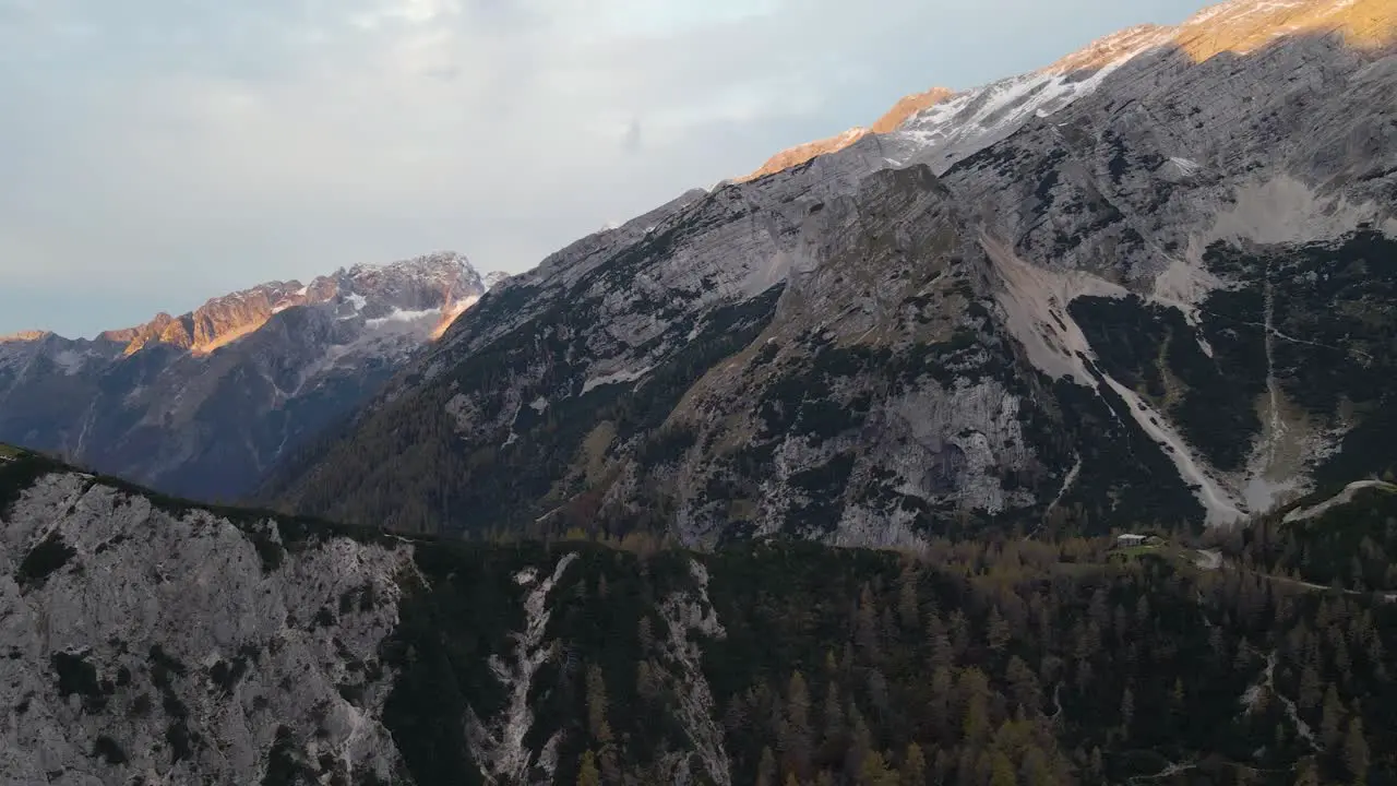 Aerial view of rough and dry mountainous terrain with sunlight falling on peak during sunrise