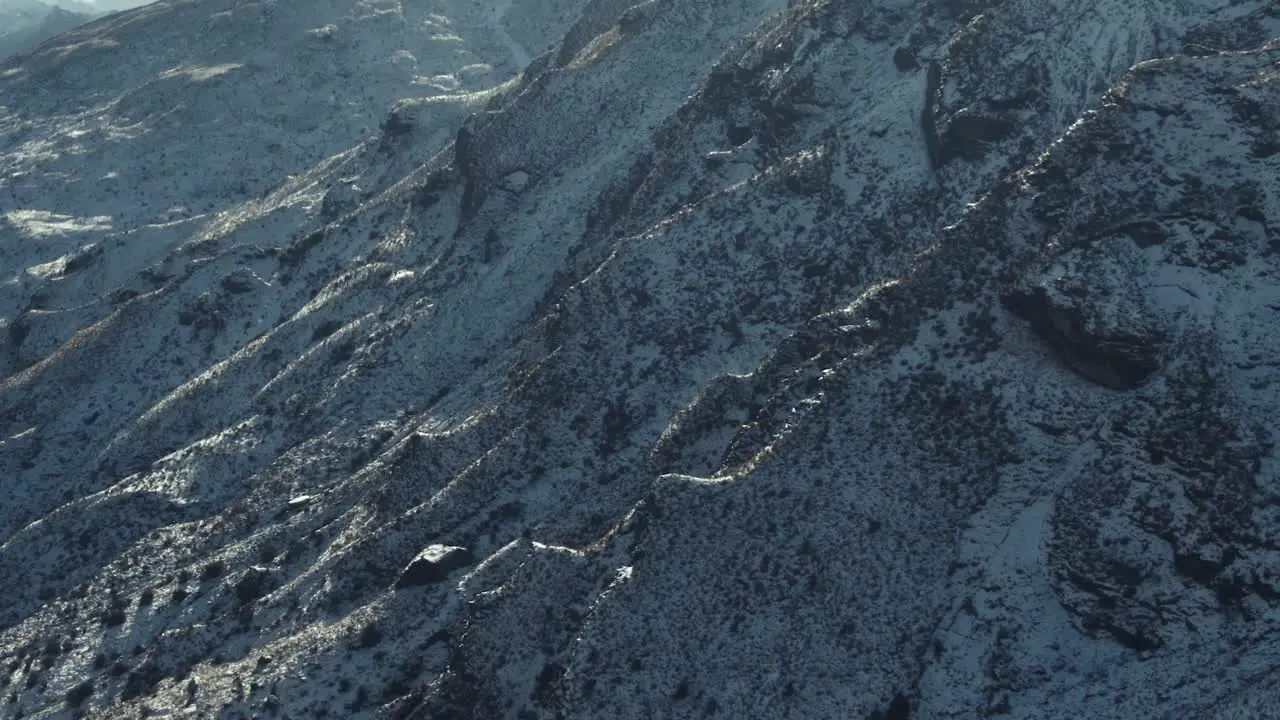 Reverse reveal of rocky snow covered mountain side in New Zealand