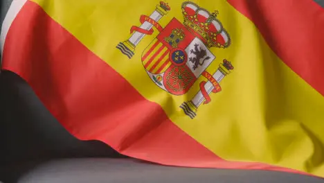 Close Up Of Flag Of Spain Draped Over Sofa At Home Ready For Match On TV