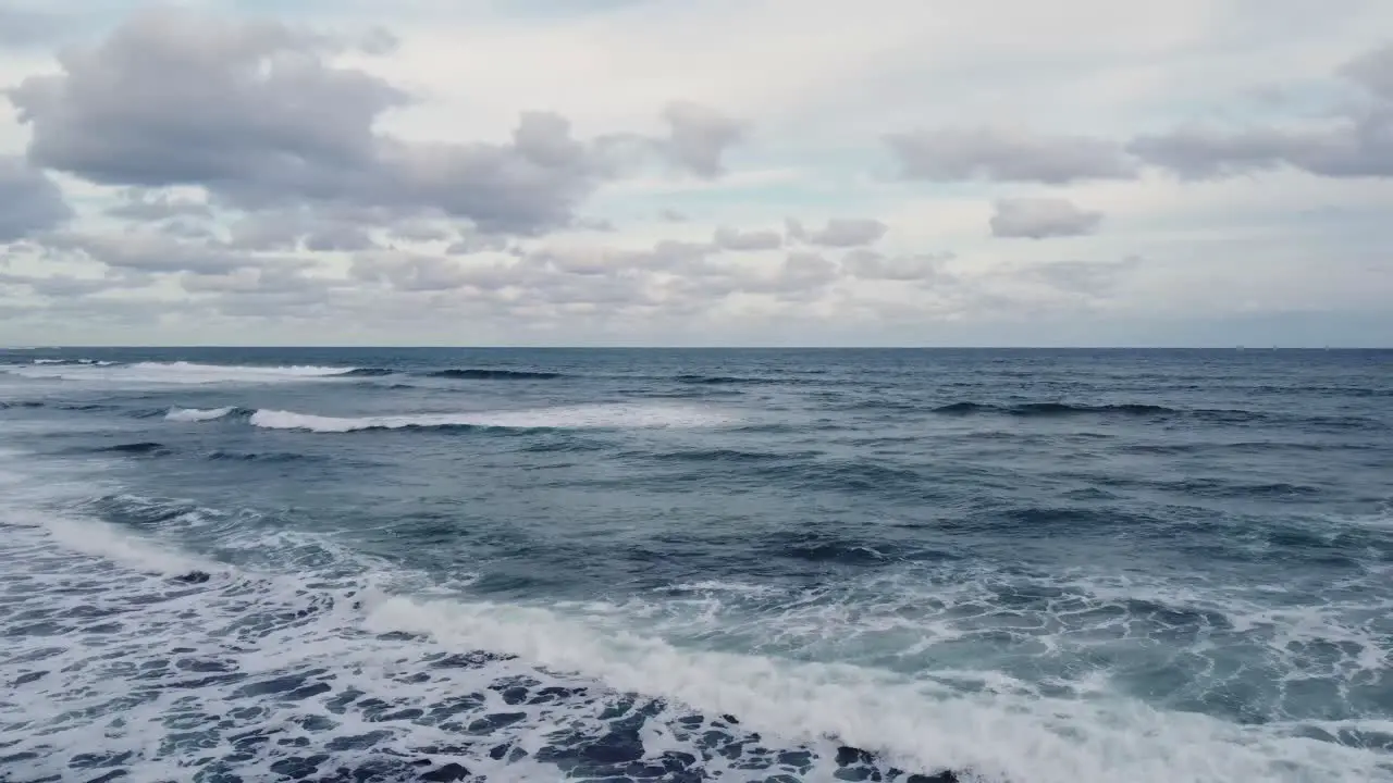 Ocean background bright blue sky with white clouds and waves at open sea approaching horizon