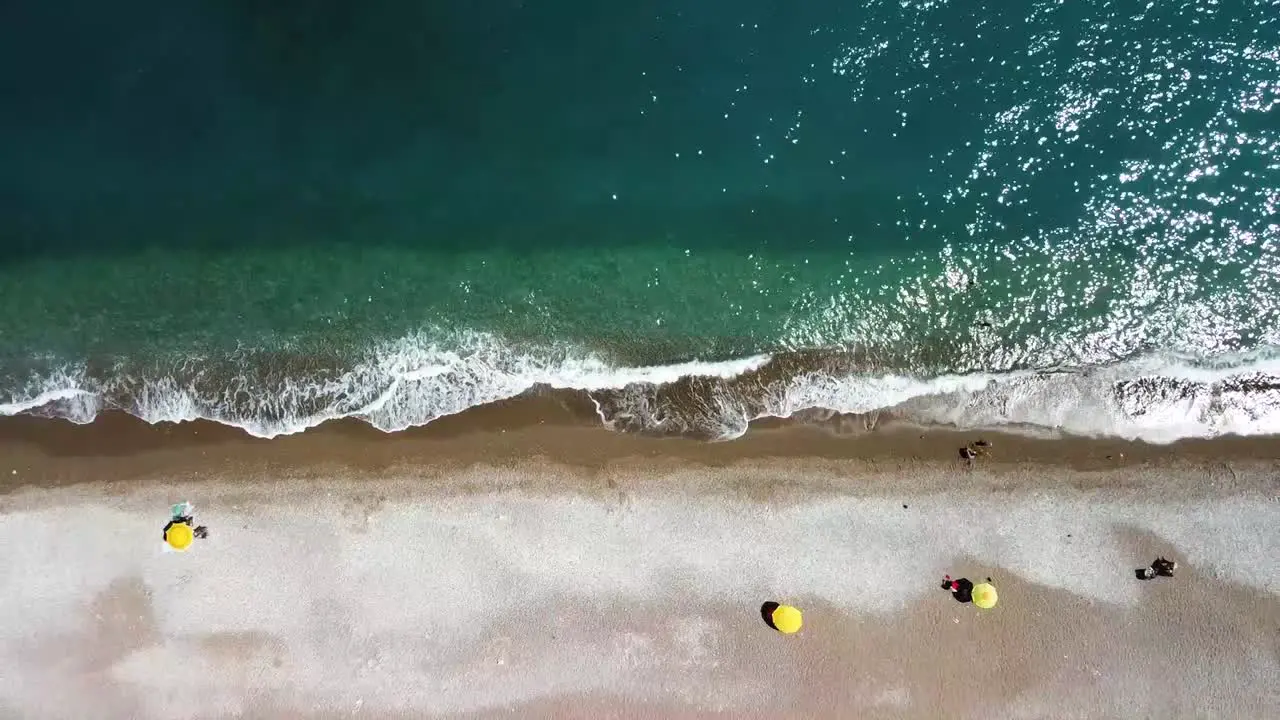 Aerial view of yellow umbrellas on a beach with crystal clear waters