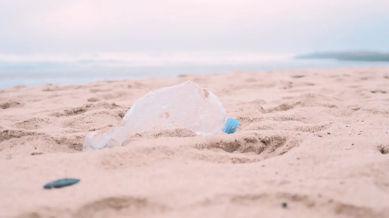 Single plastic water bottle lying on sandy beach