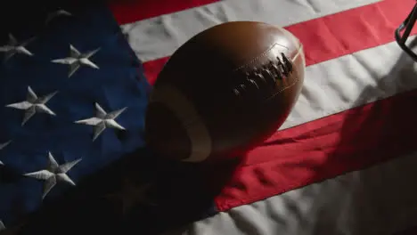 Low Key Lighting Studio Shot Of American Football With Helmet On Stars And Stripes Flag 1