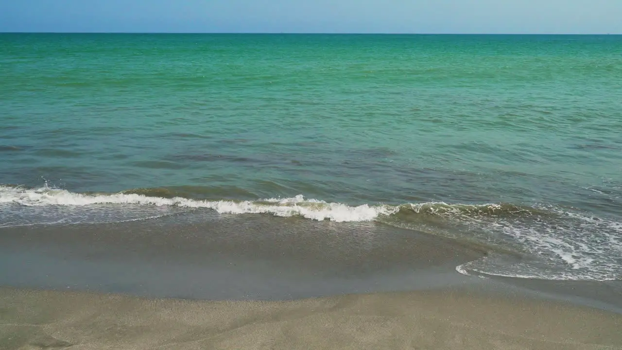 Close up shot of the small tide of the blue sea reaching the shore of the Zorritos beach Tumbes Peru