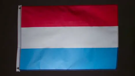 Studio Shot Of Flag Of Netherlands Collapsing Against Black Background