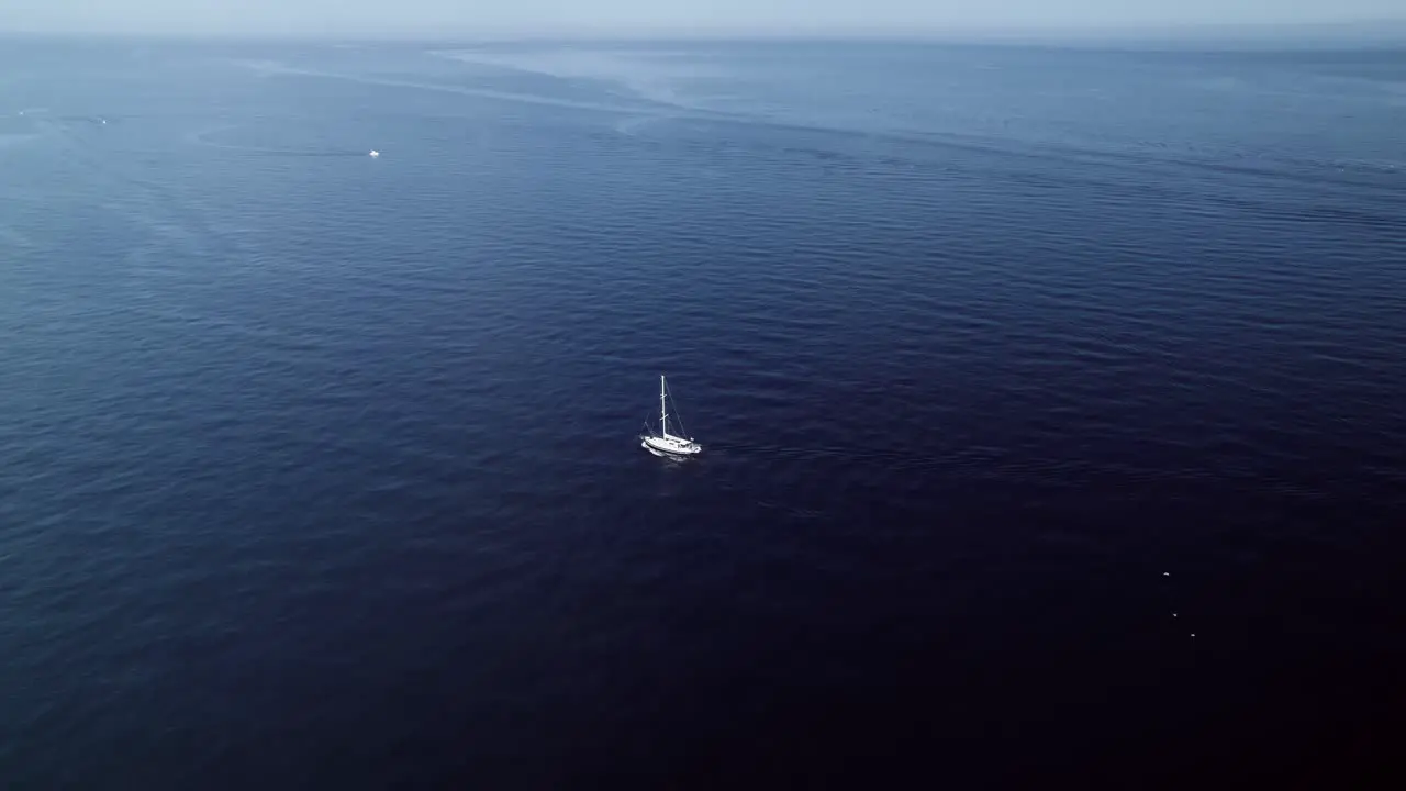 Drone flying away from the yacht sailing at the Mediterranean sea