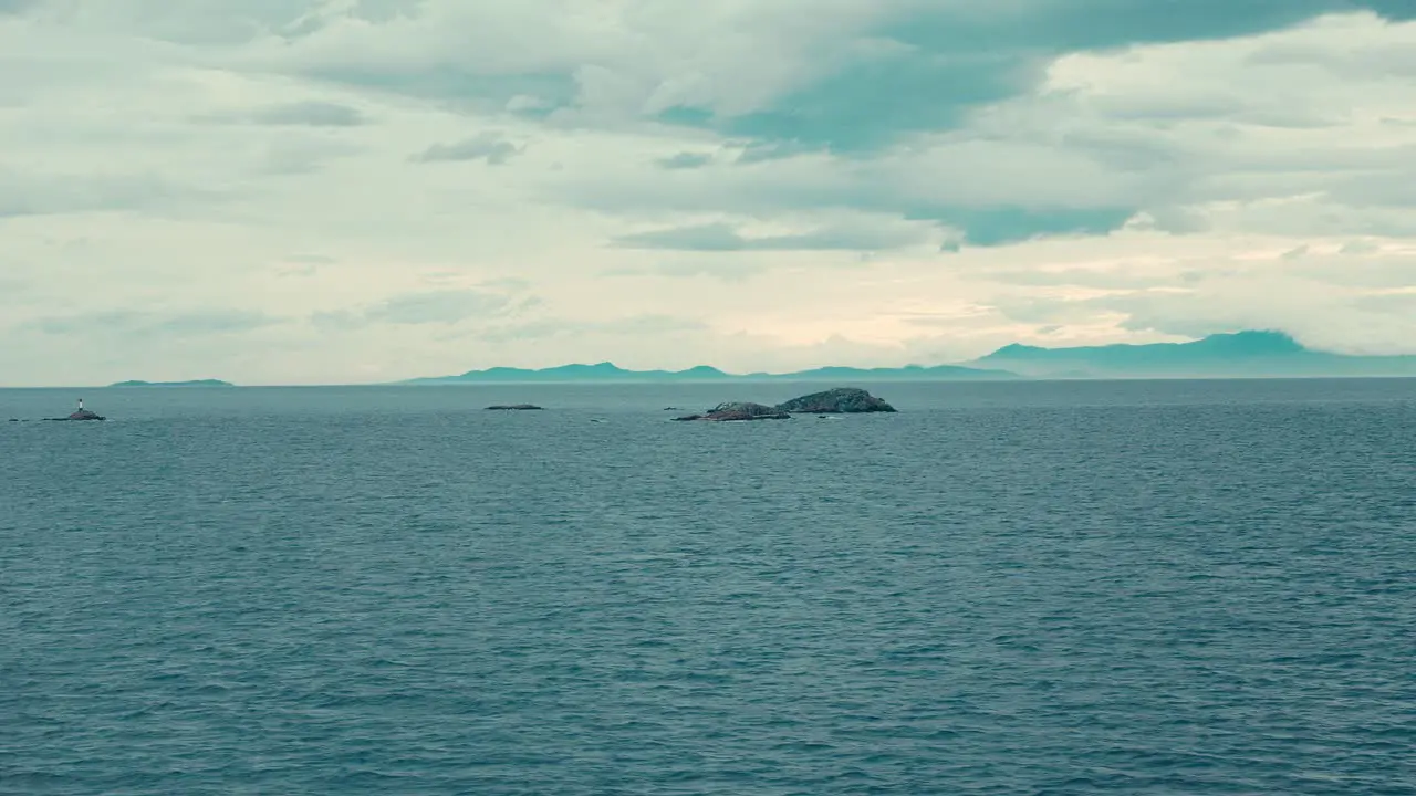 Small rocks in vast ocean with distant shoreline