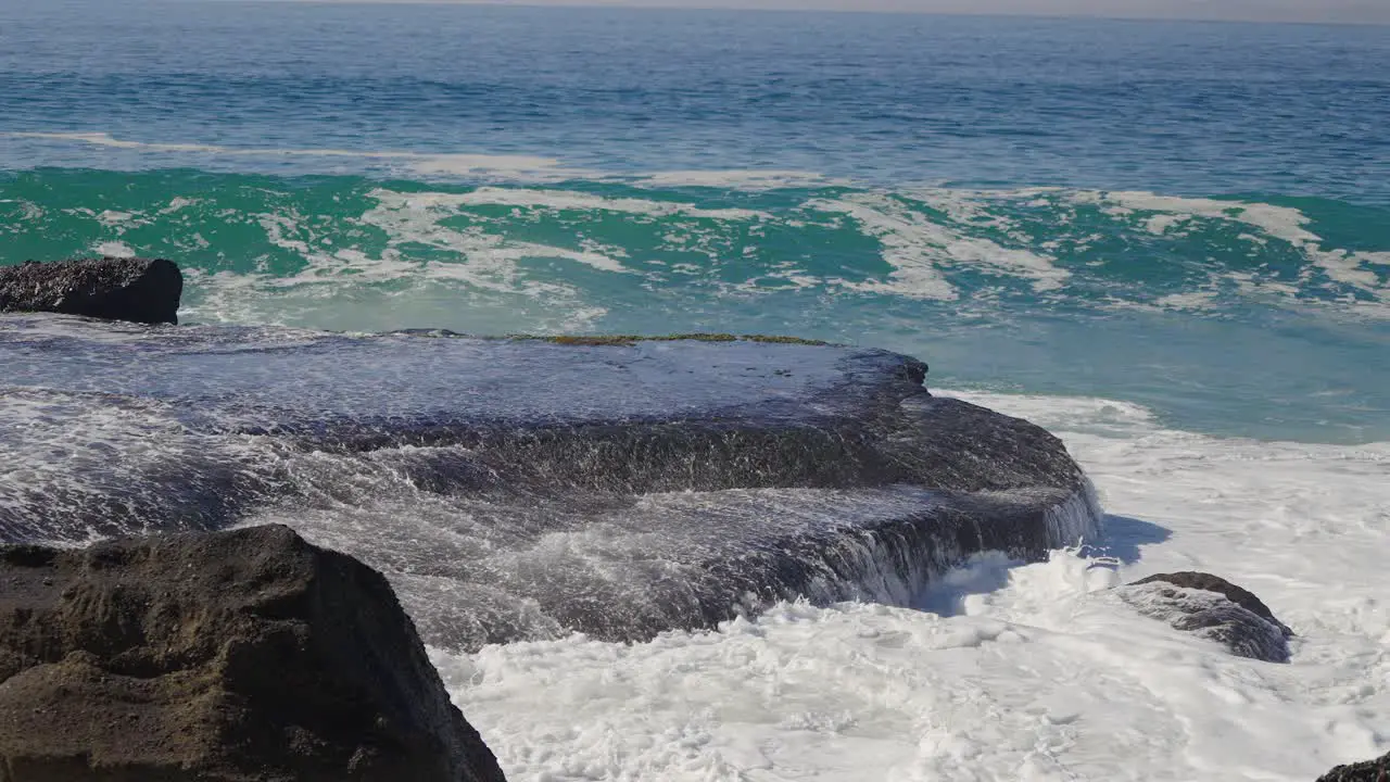 Sea water washing over a large rock as a new wave forms