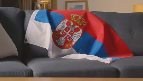 Flag Of Serbia Draped Over Sofa At Home Ready For Match On TV