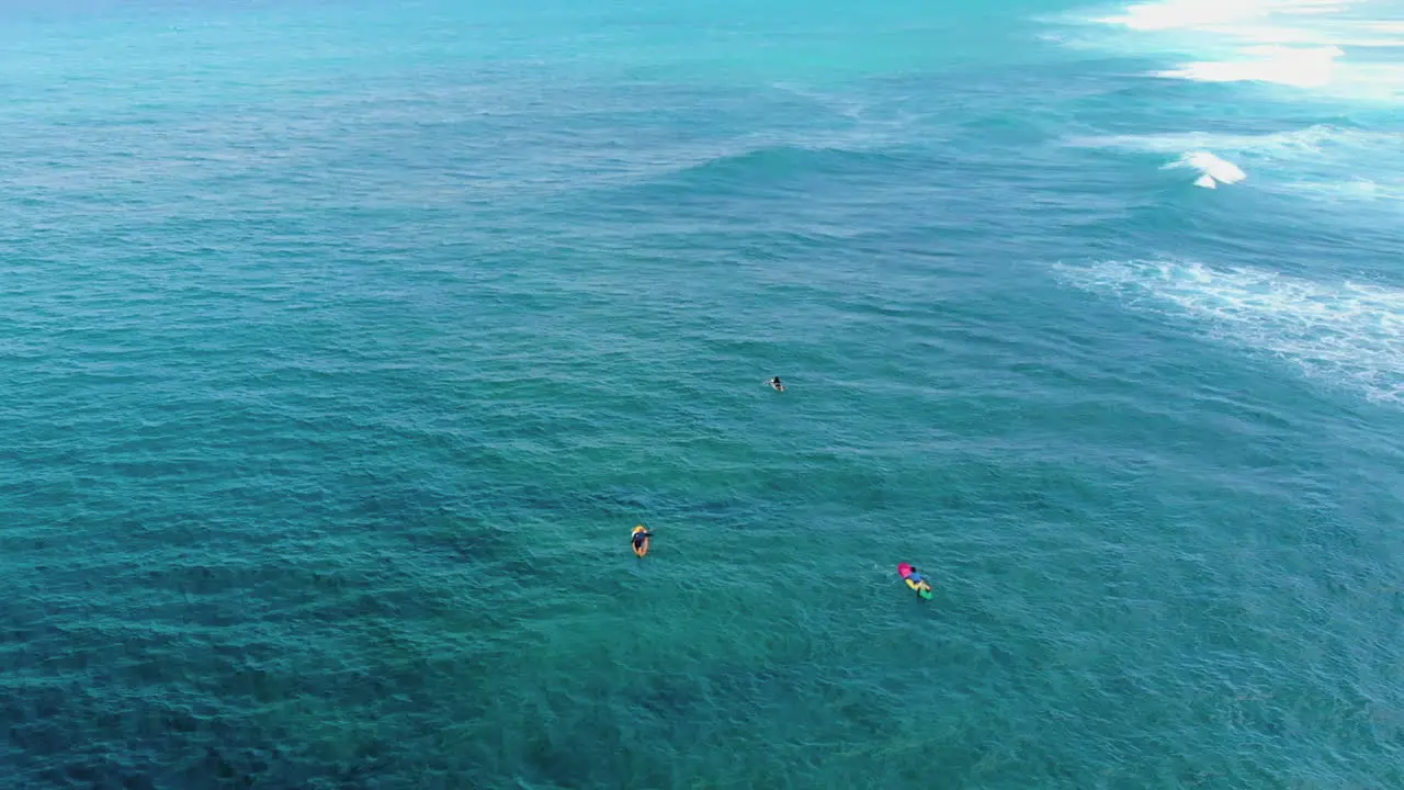 Traveller's dream location aerial footage of surfers paddling towards the ocean's white waves on a warm sunny day