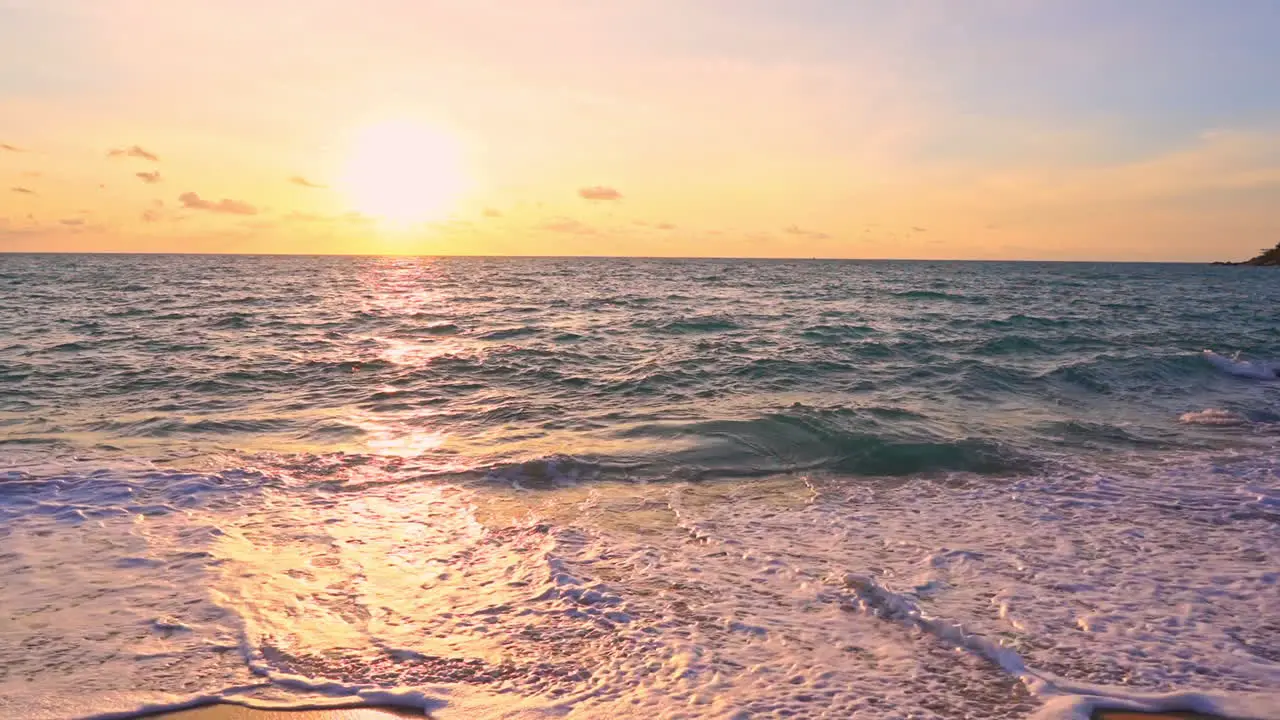 Slow-motion of incoming waves reflecting the color of the pink yellow and orange sunset