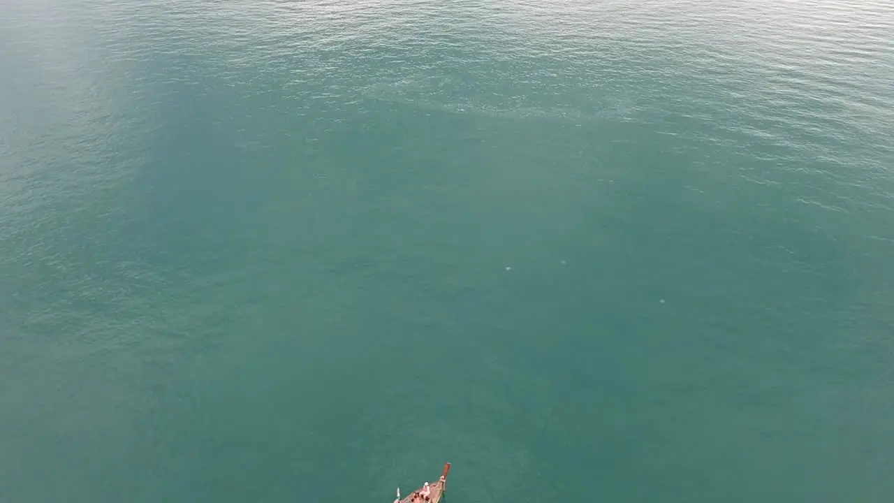 Drone footage of longtail boat navigating around islands of Krabi Thailand with the limestone rock formations sticking out of the water and the ocean in background-1