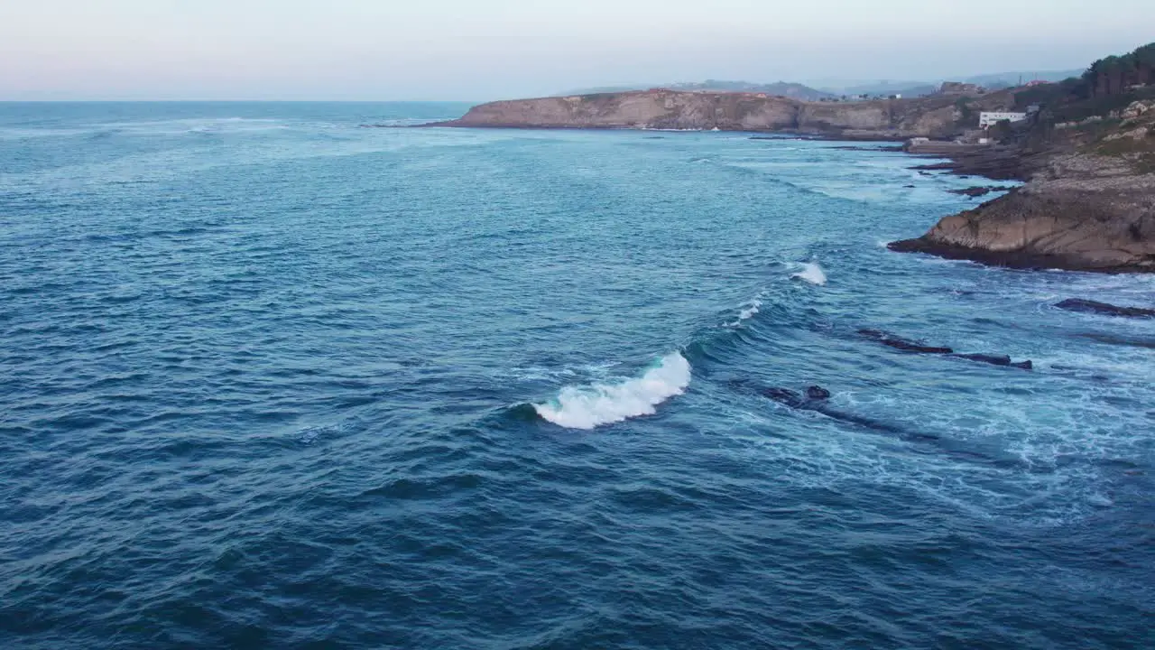 Drone Flying Towards Rocky Hill On Blue Sea