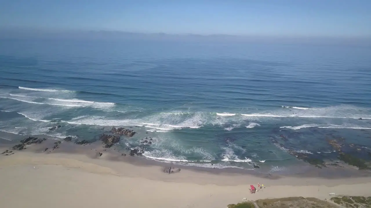 Aerial view of drone flying above beautiful beach with views of ocean waves and water crashing on to sandy beach from top angle