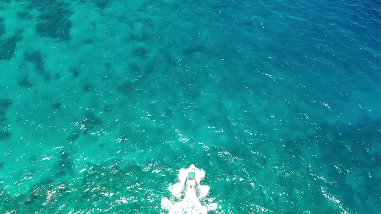 White speed boat crashing through waves in clear turquoise sea surface