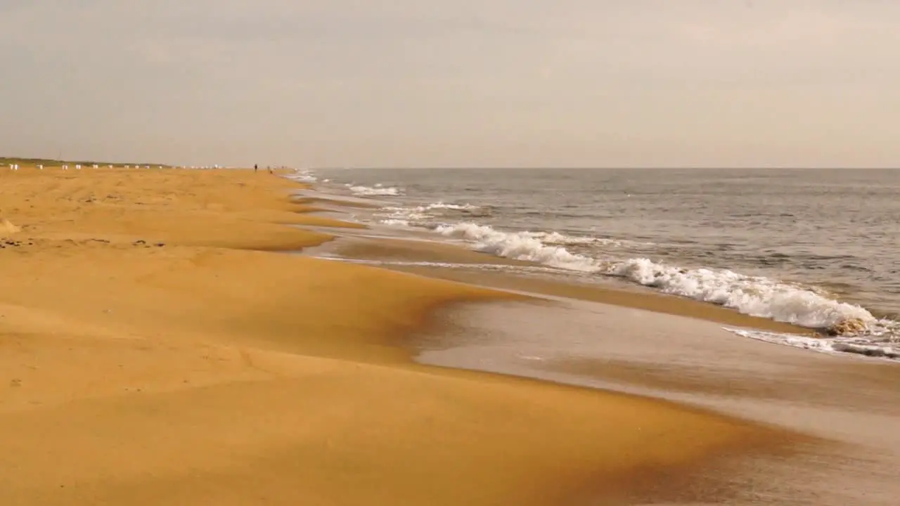 Waves crashing on golden sand beach on an overcast day