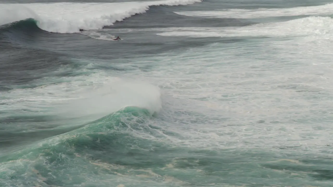 Surfing big wave in Nazare Portugal surfer and jet ski driver extreme sport wide angle view