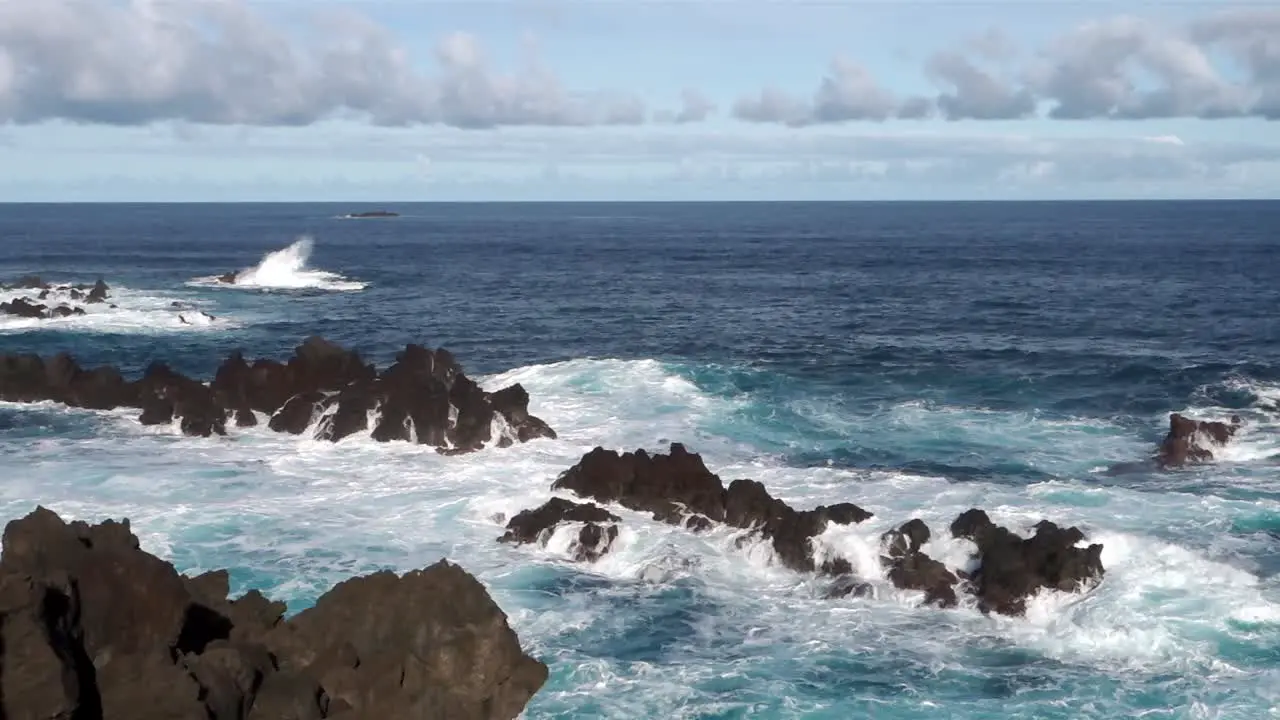 Waves crashing into rocky coast on sunny day