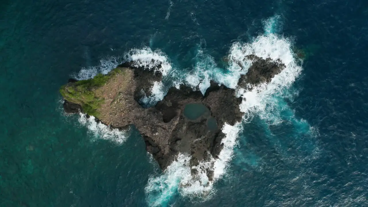 Volcanic basalt island surrounded by rough blue water of Atlantic Ocean aerial